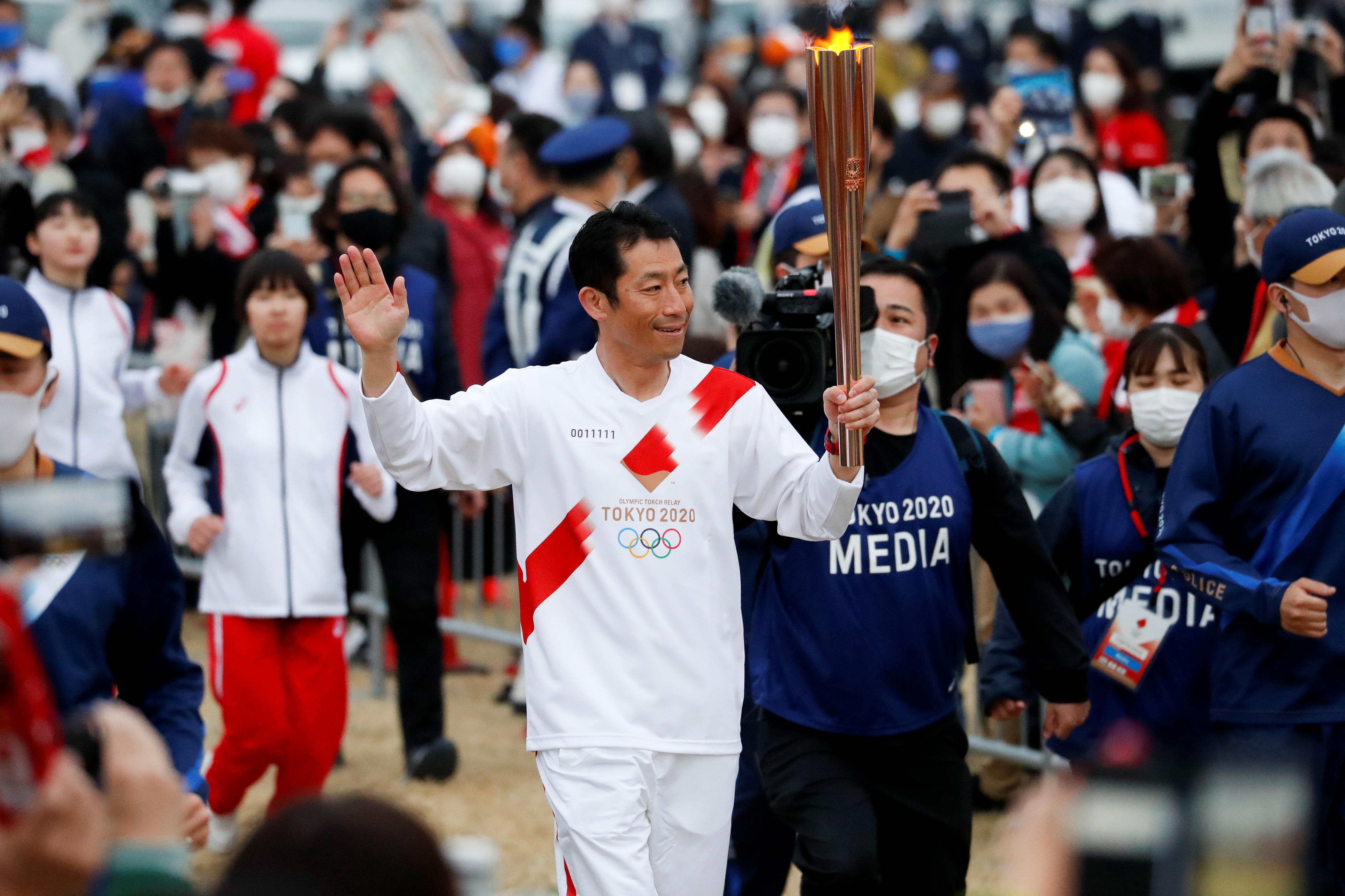 image High fives, smiles but no cheers as Olympic torch relay gets going under pandemic shadow