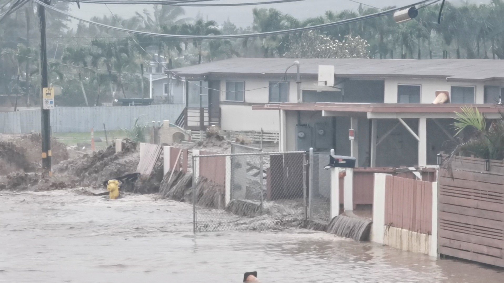 social media video grab shows floodwaters streaming down a street in hauula, hawaii