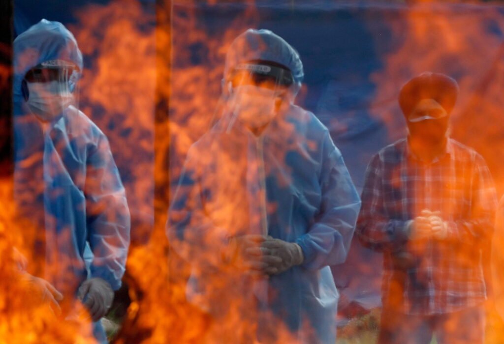 relatives stand next to the burning pyre of a man who died from the coronavirus disease (covid 19) during his cremation at a crematorium ground in srinagar