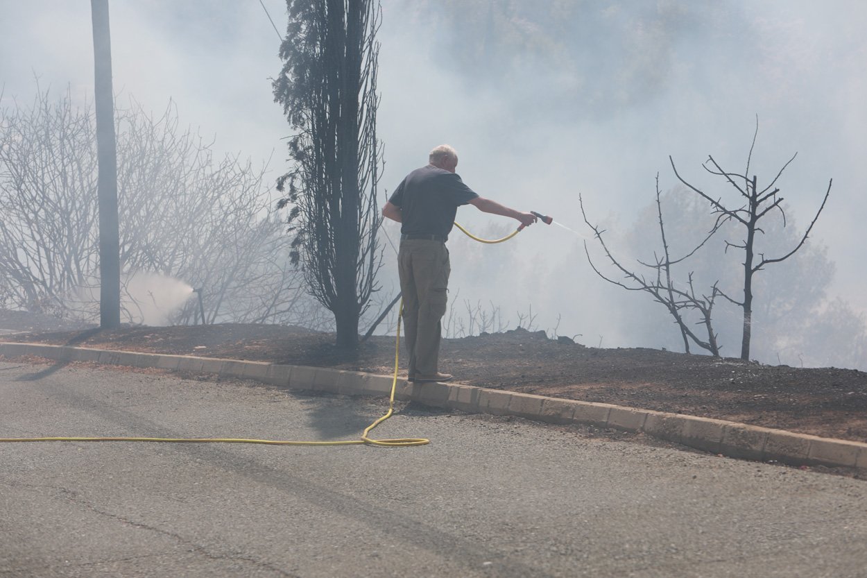 a homeowner using a hosepipe in attempt to protect his property