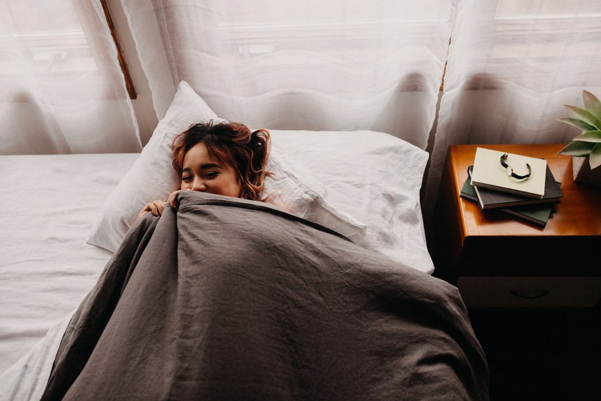 woman laughing under the covers