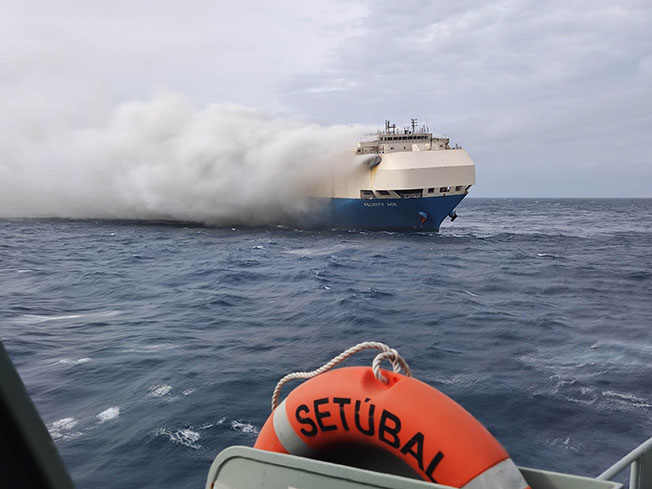 image Tug boats spray water on blazing ship carrying Porsches and Bentleys