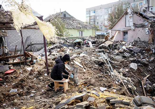 a boy plays on ruins of his grandmother's house, in kupiansk