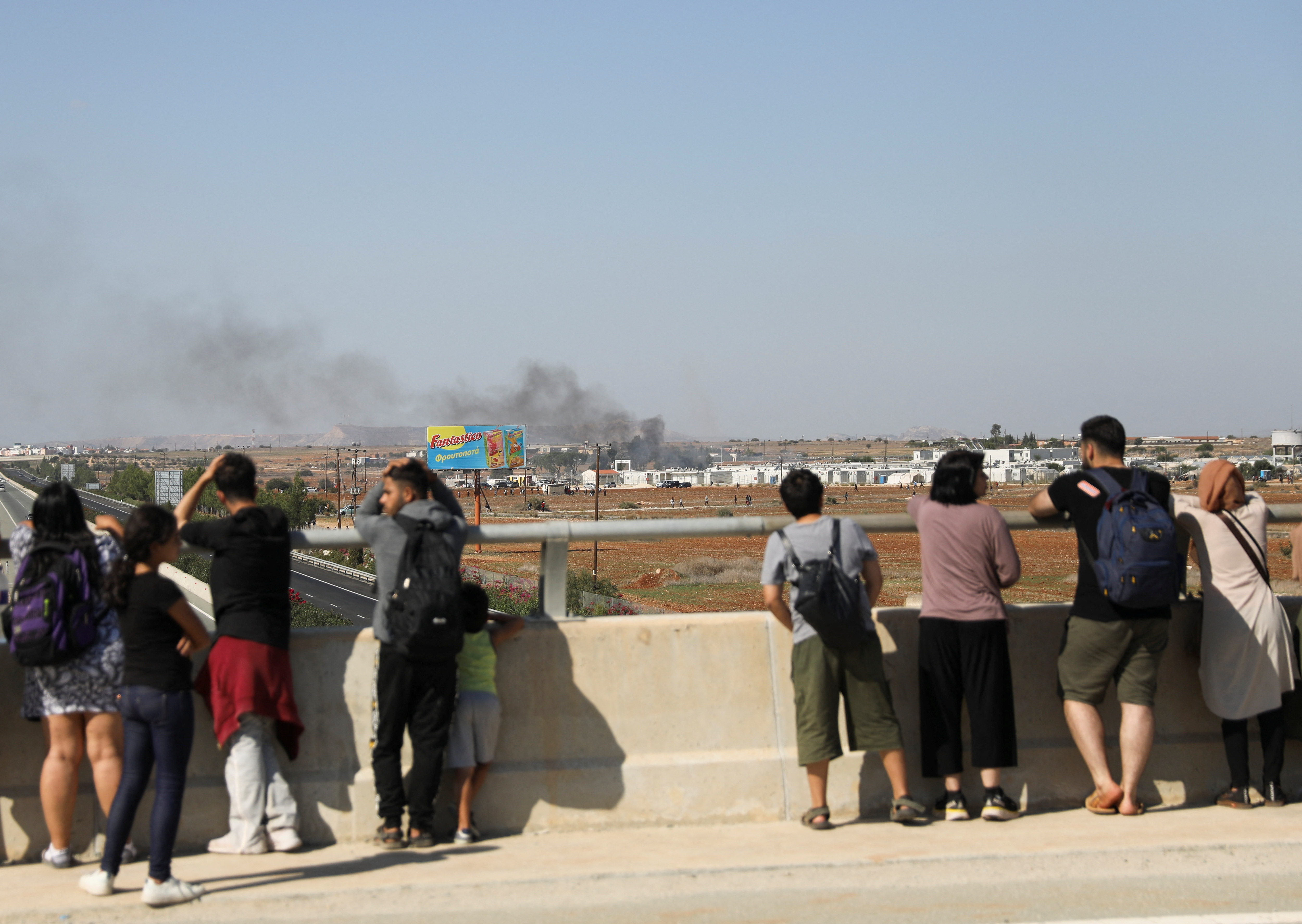 migrants watch a fire outside pournara refugee camp during clashes on the outskirts of nicosia