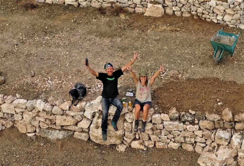 feature iole pawel and his partner justyna sitting on one of the dry walls they built