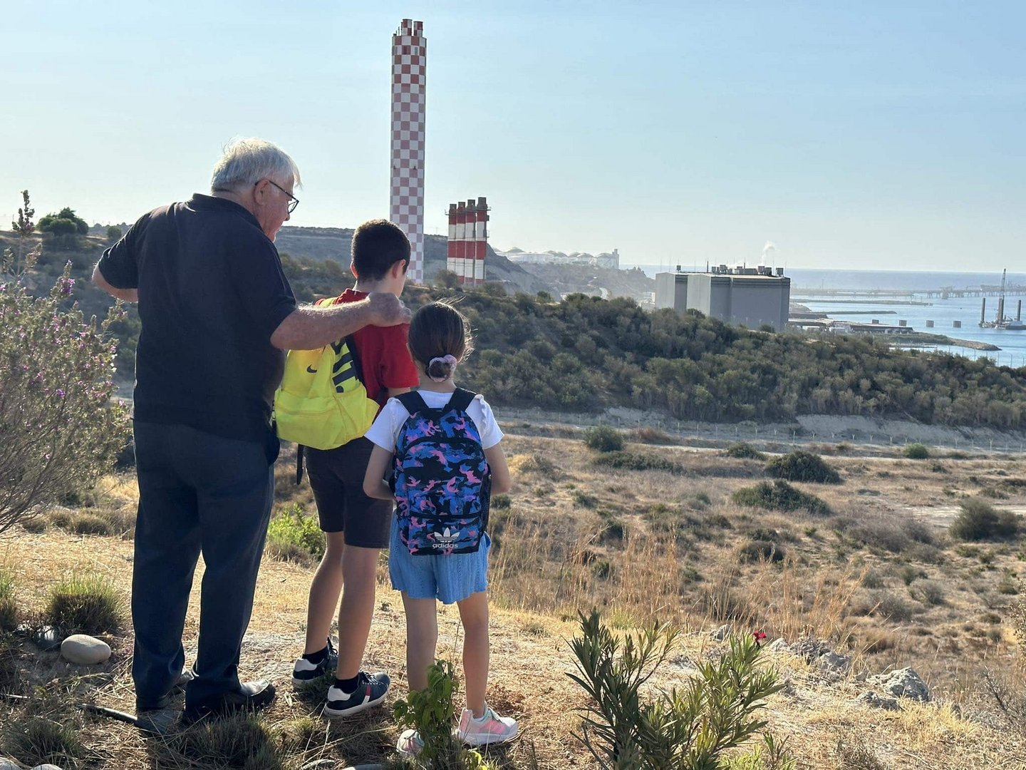a family look over at vassiliko power station, near where those who died in the blast are buried
