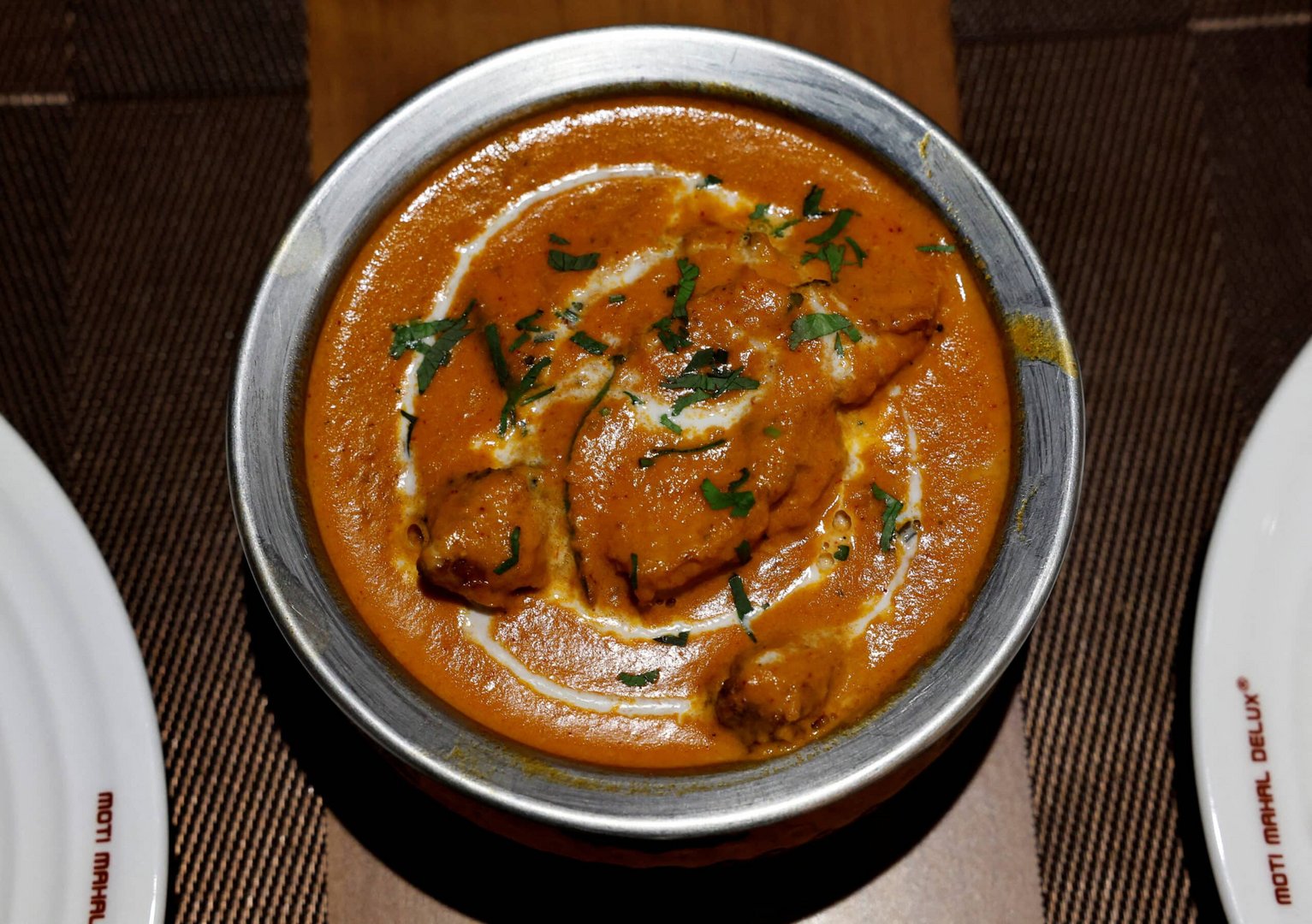 a freshly prepared butter chicken dish is placed on a table inside the moti mahal delux restaurant in new delhi