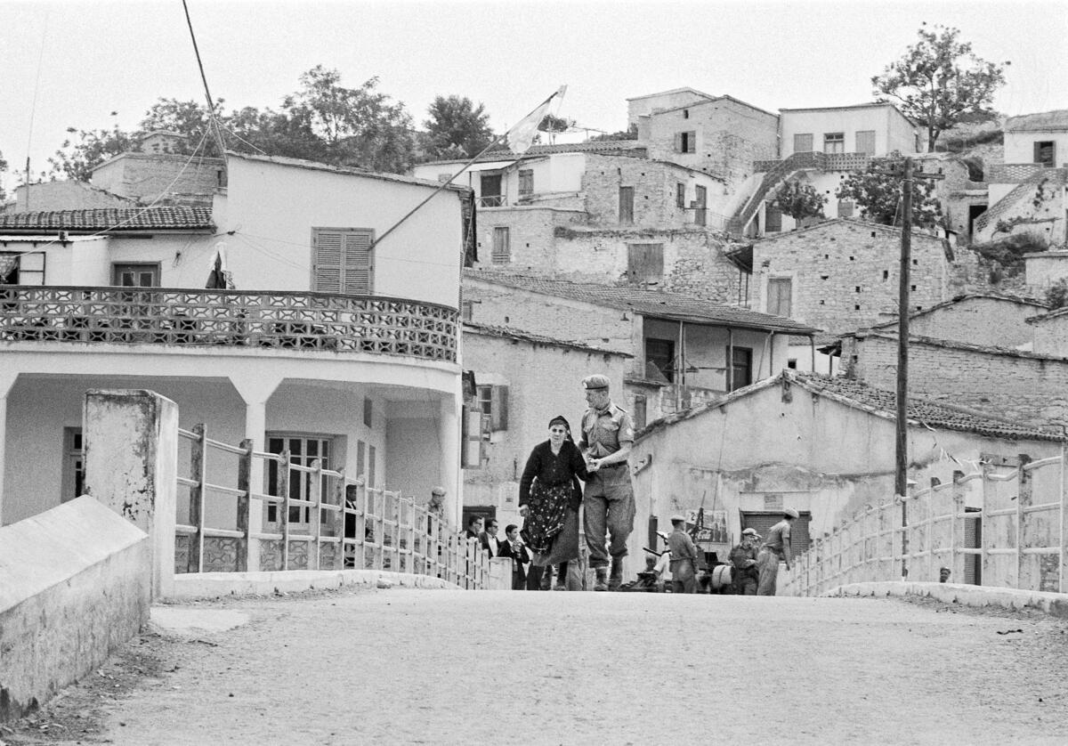 feature tom pfc. tony hindley (right) escorted an elderly greek woman, maris atteshlis, across the bridge from the turkish sector to the greek sector of ayios theodoros in 1964
