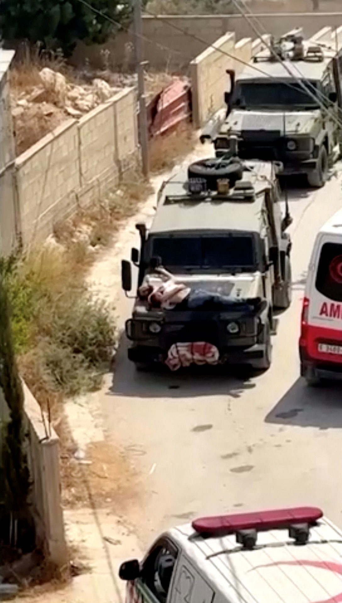 image Israeli forces strap wounded Palestinian to jeep during raid